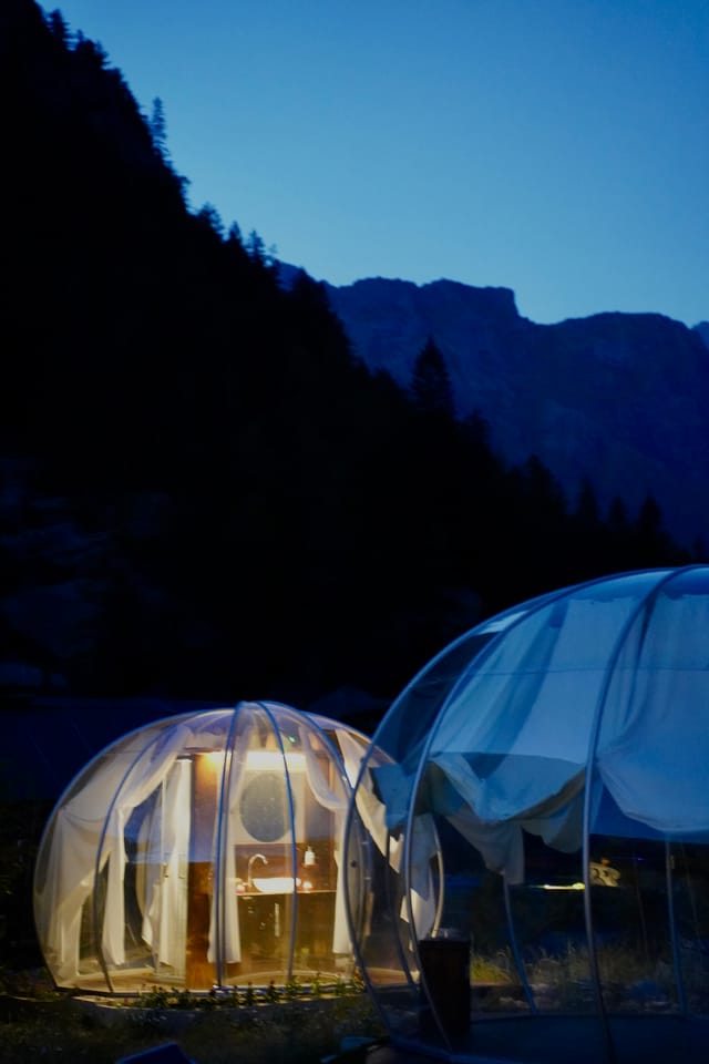 Bolla glamping al crepuscolo con montagne blu
